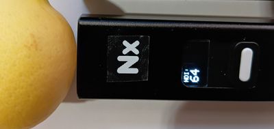 Close-up of a black digital device with a display showing '64' next to a yellow fruit.