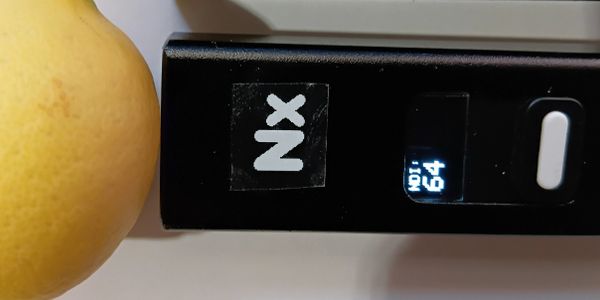 Close-up of a digital device with a screen displaying 'Vol 64' next to a yellow fruit.