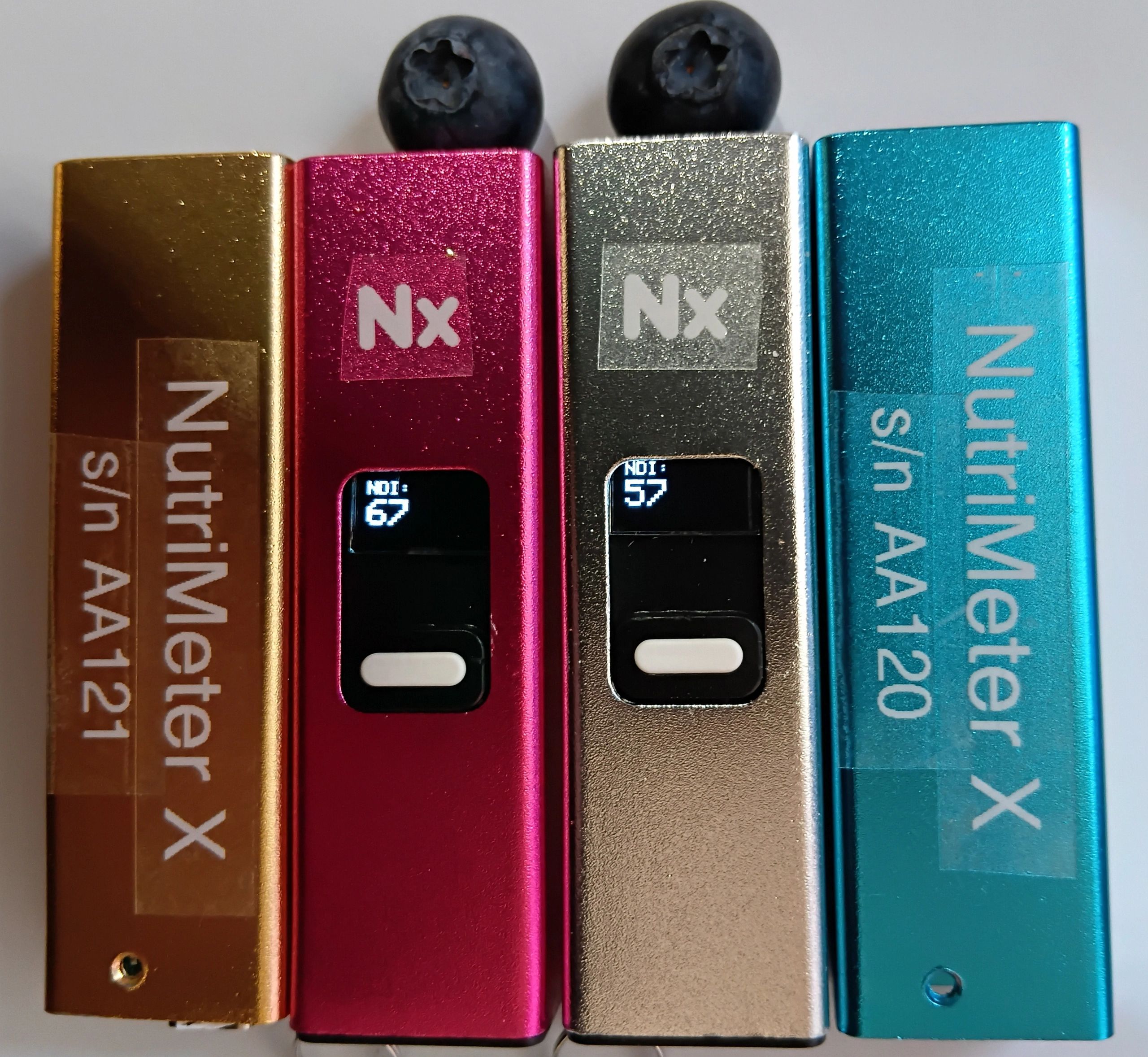 Four colorful NutriMeter X devices with blueberries on top.