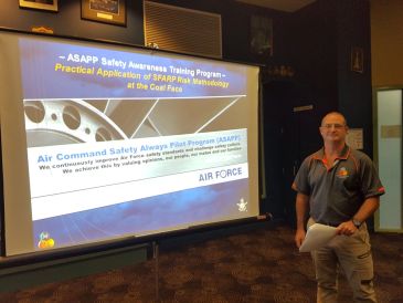 Man presenting an Air Force safety awareness program in a conference room.