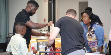 People interacting at a food or drink service table indoors.
