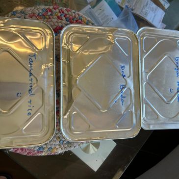 Three aluminum food trays labeled with different food items.