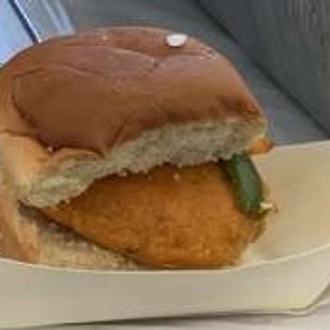 A breaded fish fillet sandwich with pickles in a soft bun.