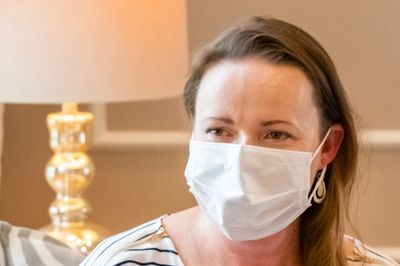 Lactation consultant wearing a mask holding a breast pump facing woman.