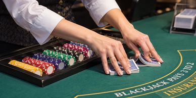 Dealer shuffling cards at a blackjack table with chips.