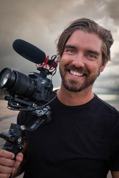 Male model smiling holding video camera Jack Tree Vancouver cinematographer videographer