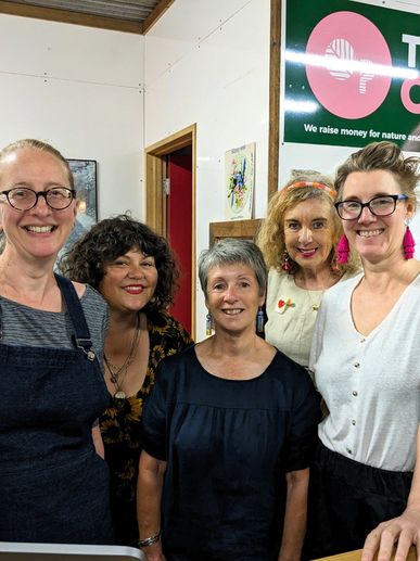 Five women smiling together indoors, showcasing friendship and warmth.