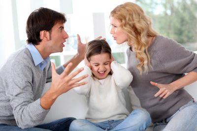 Parents arguing while child covers ears.