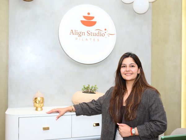 A woman smiling inside Align Studio Pilates with a welcoming pose.