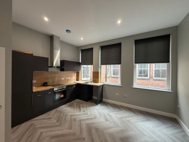 Modern kitchen with black cabinets and wood accents under soft ceiling lights.