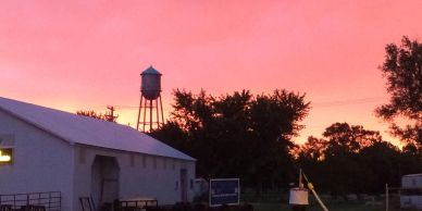 Sunset over a rural farm with a water tower.