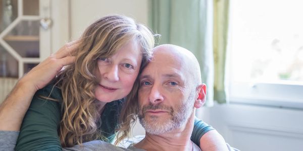 Affectionate middle-aged couple embracing and looking at the camera.