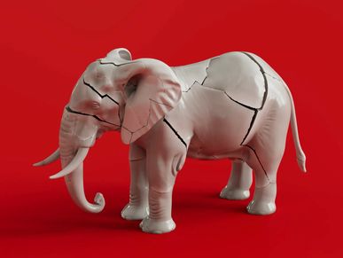 Broken porcelain elephant sculpture on red background.