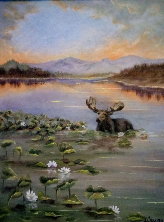 Moose in a lake with lily pads and mountains in the background.