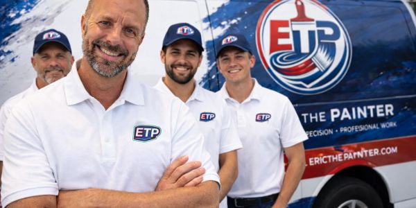 Four smiling painters in ETP uniforms standing in front of their company van.