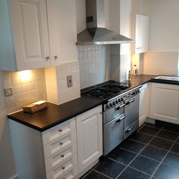 Modern kitchen with white cabinets, black countertops, and stainless steel stove.