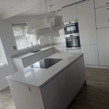 Modern kitchen with white cabinets, white countertops, and glass hob.