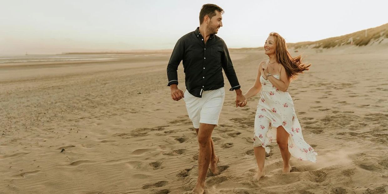 couple running along the beach holding hands 