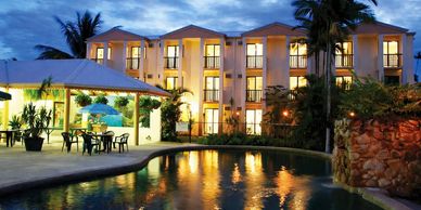 A warmly lit hotel with a pool and outdoor seating at dusk.