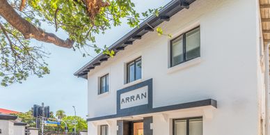 Modern white building with ARRAN sign and black trimmed windows.