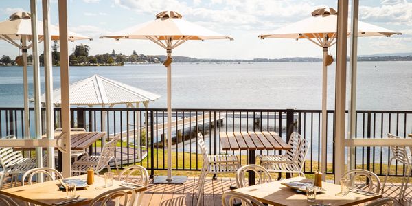 Outdoor dining area overlooking a lake with umbrellas.