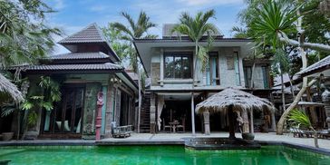 Modern house with pool surrounded by tropical plants.