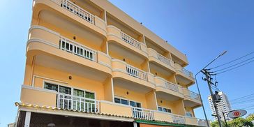 Yellow four-story apartment building under a clear sky.