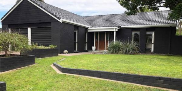 Black house with a green lawn.