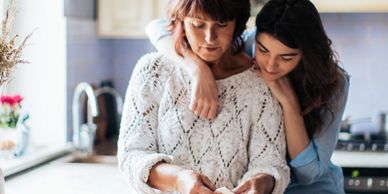 Mother and Daughter embracing while cooking in kitchen