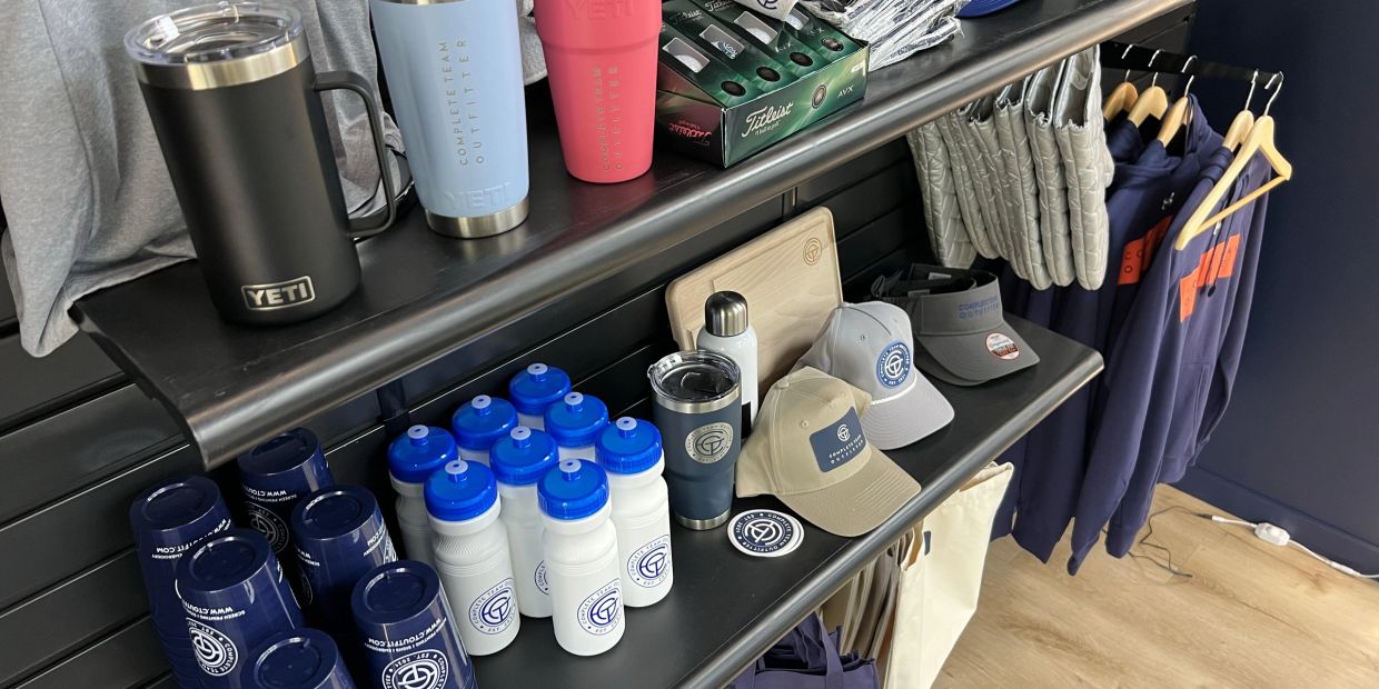 Promotional items displayed on shelves at the Complete Team Outfitter showroom.