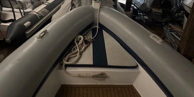 Interior front view of a small inflatable boat with coiled ropes.