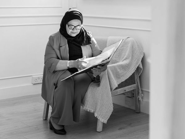 Elderly woman in a hijab reading a photo album.