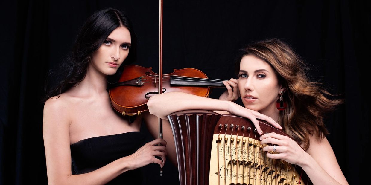 Violinist and harpist standing next to each other while holding their instruments. 