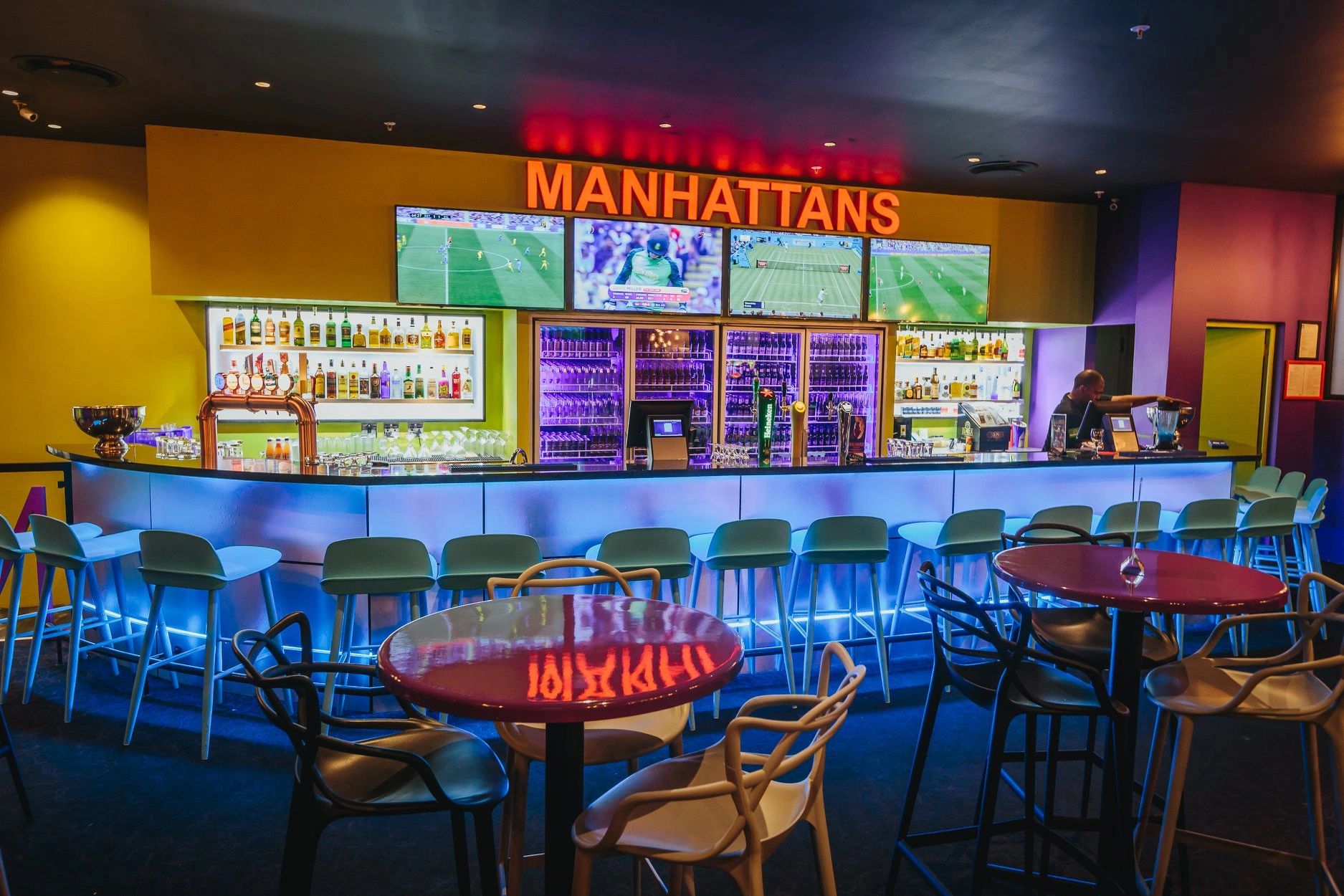 Modern bar with bright lights and TV screens.