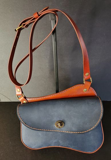 Leather crossbody bag with a navy front and brown strap.