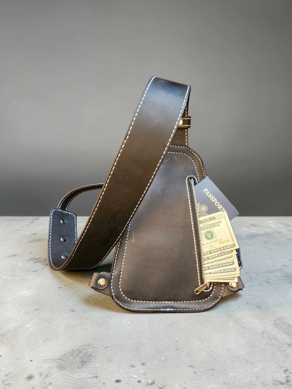 Brown leather sling bag with passport and money in side pocket.