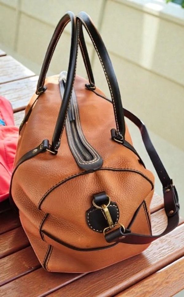 Stylish brown leather handbag with black handles and gold clasp detail.