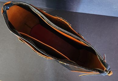 Top view of an open leather bag with a zipper.