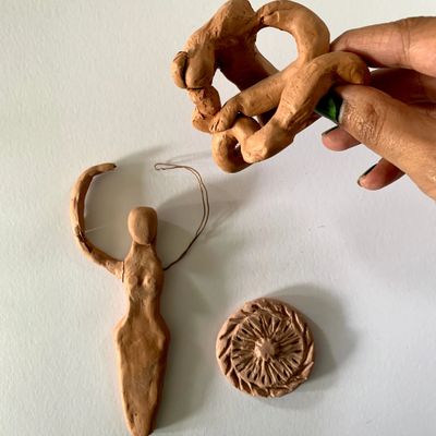 Handcrafted clay art pieces including a female figure, a circular patterned item, and an abstract shape.