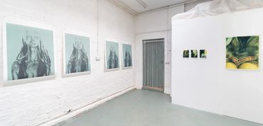 Art gallery with framed portraits and abstract paintings on white walls.