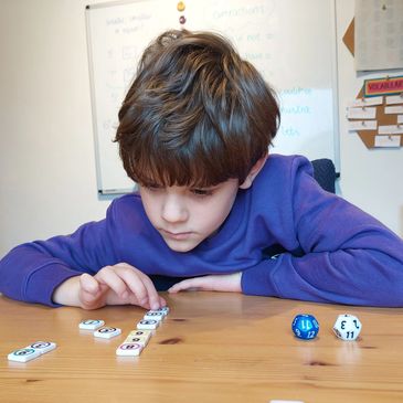 Maths tuition: child practising arithmetic using a number tiles game 