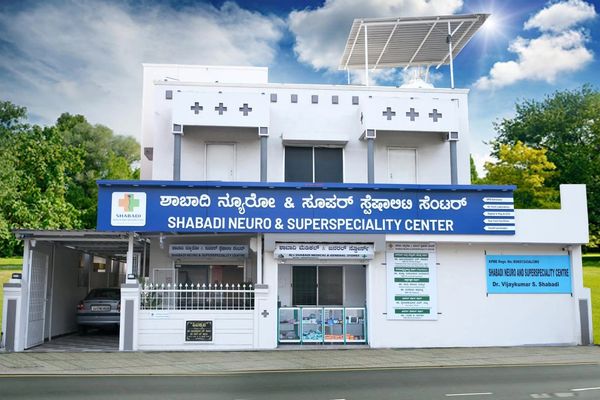 Modern white medical center with blue signage in Kannada and English.