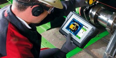 Technician using a tablet and laser tool for machinery alignment.