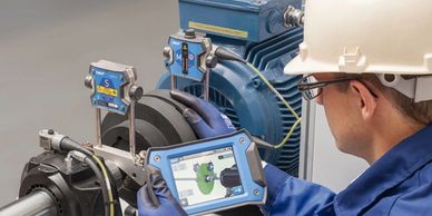 Engineer using a handheld device to monitor industrial machinery.