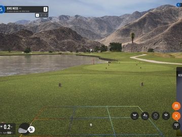 A serene golf course set against mountainous terrain with a water hazard.