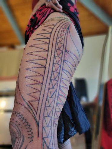 Close-up of a leg with intricate tribal tattoo designs in black ink.