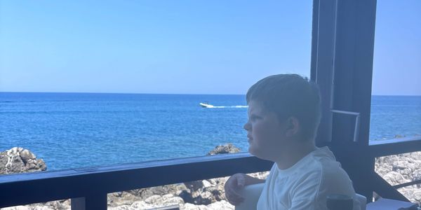 Boy looking at the sea from a balcony.