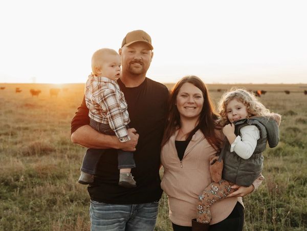 Family of four posing outdoors at sunset in a field.