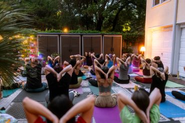 A group practicing yoga outdoors in the evening on mats.