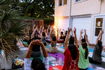 A group practicing yoga outdoors in the evening.